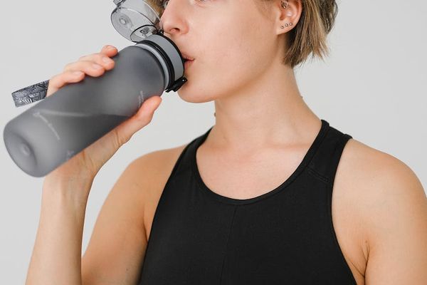 Person drinking water from a reusable bottle after a workout.